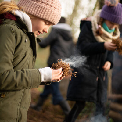 Young girl makes a fire at the Finnebrogue Woods School of Bushcraft Easter Camp
