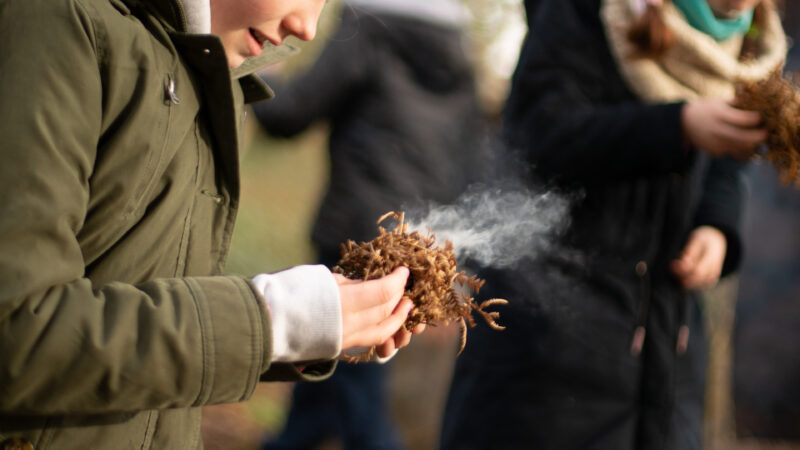 Young girl makes a fire at the Finnebrogue Woods School of Bushcraft Easter Camp