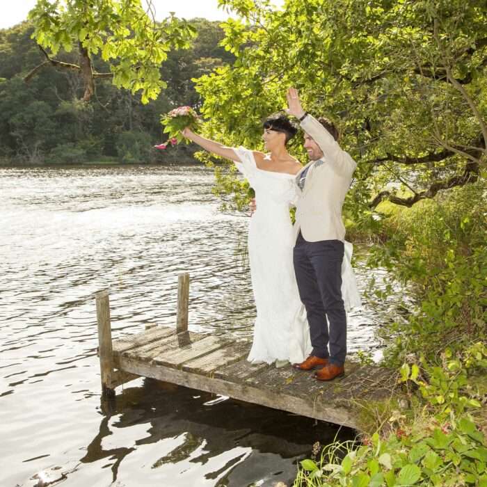 Wedding couple wave to guests over Finnebrogue Lake