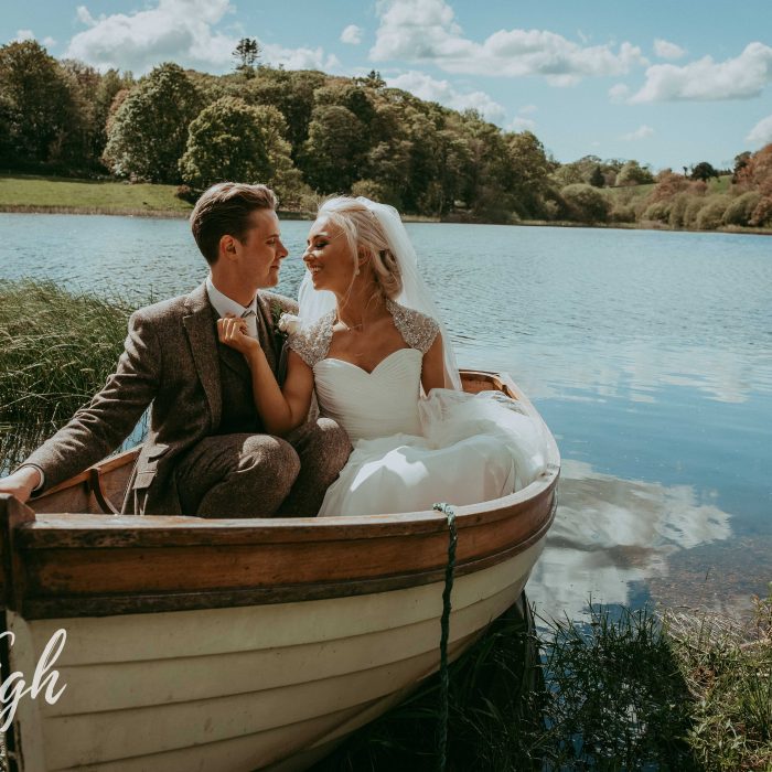 Newly married couple gaze at eachother while sitting in a rowing boat on Finnebrogue Lake