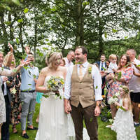 A wedding party celebrates a newly married couple, throwing dried leaves confetti over them in our magical ceremony site