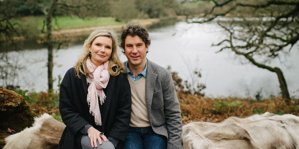 Ed & Rachael sit at the firepit area on a large log overlooking Finnebrogue Lake