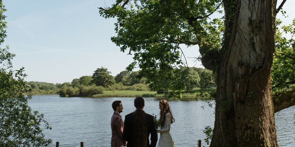 A wedding ceremony takes place overlooking a lake at Finnebrogue Woods