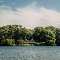 Stunning photograph of Finnebrogue Woods Tipi wedding venue with ancient woodland surrounding it and the lake in front