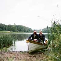 Two men sit in a rowing boat at the edge of Finnebrogue Lake