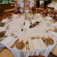 Round tables are decorated with setting and simple centrepieces inside a wedding tipi