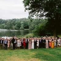 A whole wedding party stand in front of Finnebrogue Lake at our tipi wedding venue