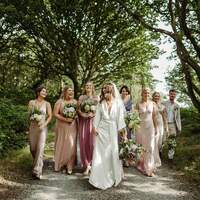 Bride & her bridesmaids walk down a path through the woods at Finnebrogue Woods