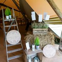 Rustic wooden crates and plants stand at the entrance of a Tipi wedding to welcome guests