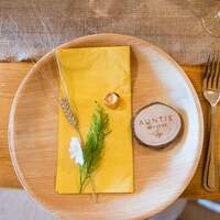 Rustic wooden place settings with yellow napkins are decorated with wheat and wooden name settings