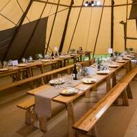 Rustic wedding vibes inside a Tipi with hessian table runners and wooden tables & benches