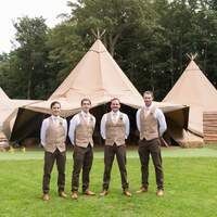 Four groomsmen stand in front of the wedding tipis at Finnbrogue Woods