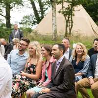 Wedding guests sit on benches at the ceremony site at Finnebrogue Woods