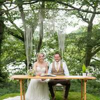 The bride & groom sign the registrar on a wooden picnic table