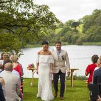 Bride & groom walk down the aisle, Finnebrogue Lake and woods is behind them
