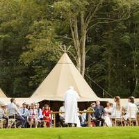 A wedding reception takes place at Finnebrogue Woods, Tipis stand behind the ceremony