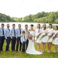 The wedding party pose for photographs in front of the lake