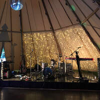 A band sets up on a stage inside a Tipi for Allen & Overy Corporate Summer Party